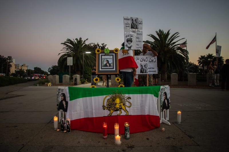 iranian flag and photos of mahsa amini with candles
