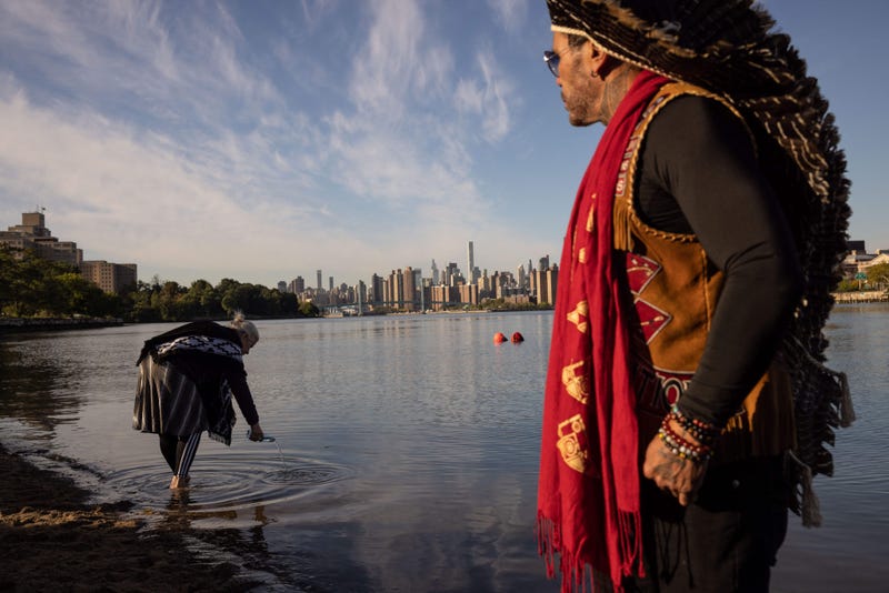 A woman pours water into the East River during an Indigenous Peoples' Day sunrise ceremony on Randall's Island in New York City on October 10, 2022.