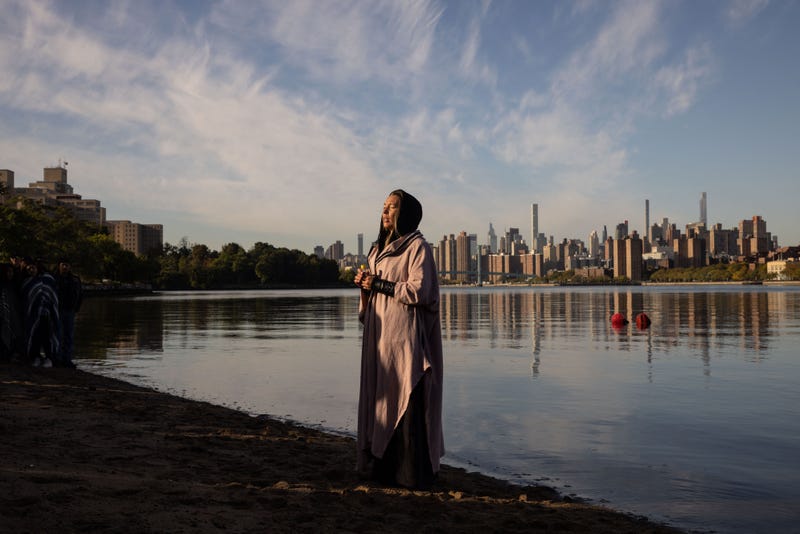 A woman prays while holding a container of water brought from Puerto Rico during an Indigenous Peoples' Day sunrise ceremony on Randall's Island in New York City on October 10, 2022.