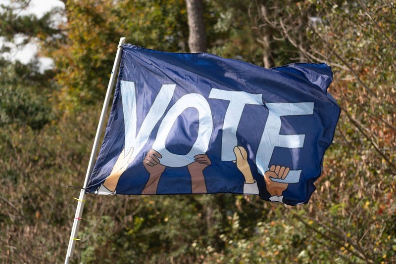A flag reading VOTE waves as Senator Raphael Warnock (D-GA) meets with community members to encourage them to come out and vote on the first day of early voting on October 17, 2022 in Duluth, Georgia. The Democratic incumbent, Warnock is running against Republican candidate Herschel Walker for the Senate seat in Georgia. (Photo by Megan Varner/Getty Images)