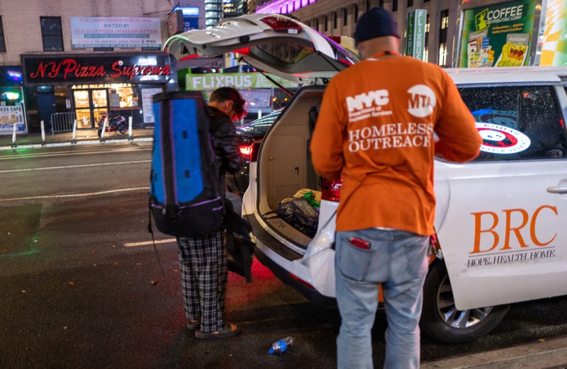 A homeless New Yorker puts his bag in an outreach workers van at Penn Station.