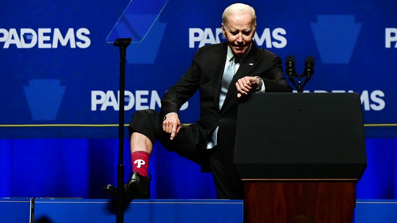 President Joe Biden reveals a sock with the Philadelphia Phillies logo and checks his watch to see the time before the first game of the World Series as he addresses supporters during the Democratic Party's Independence Dinner on October 28, 2022 in Philadelphia, Pennsylvania. Election Day will be held on November 8.