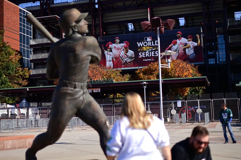 Sports fans walk past a World Series banner at Citizens Bank Park.