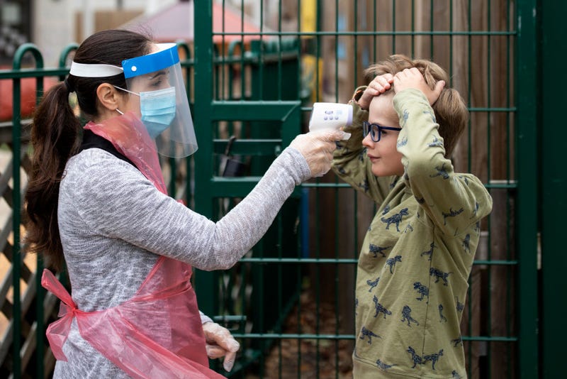 A member of staff wearing personal protective equipment (PPE) takes a child's temperature at the Harris Academy's Shortland's school on June 04, 2020 in London, England.