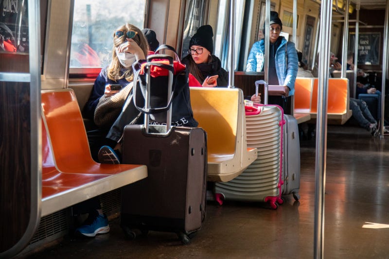 Travelers ride the subway to John F. Kennedy International Airport on Nov. 23, 2022