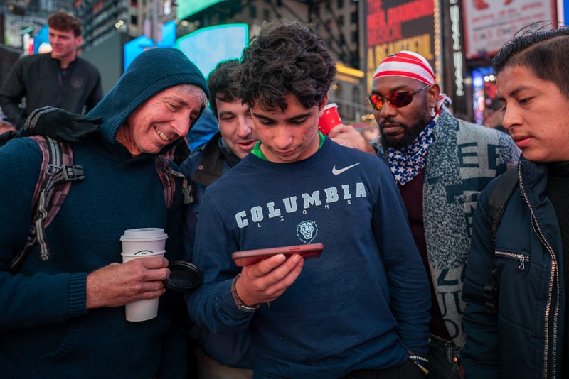 World Cup fans switch to their cellphones as the game is cut off from the screens at Times Square during the U.S. match against England on November 25, 2022 in New York City.  