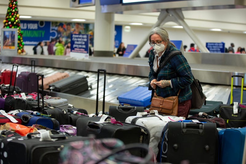 woman looks out over a sea of luggage near a baggage claim