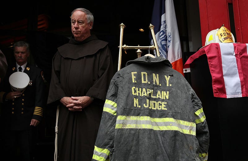 A friar stands near a bunker coat and helmet belonging to FDNY chaplain Mychal Judge during a memorial service and dedication ceremony to induct the two items into the permanent display at the New York City Fire Museum on September 11, 2011 in New York City. New York City firefighters are commemorating the 10th anniversary of the 9/11 terrorist attacks and honoring the 343 firefighters who died in the line of duty.