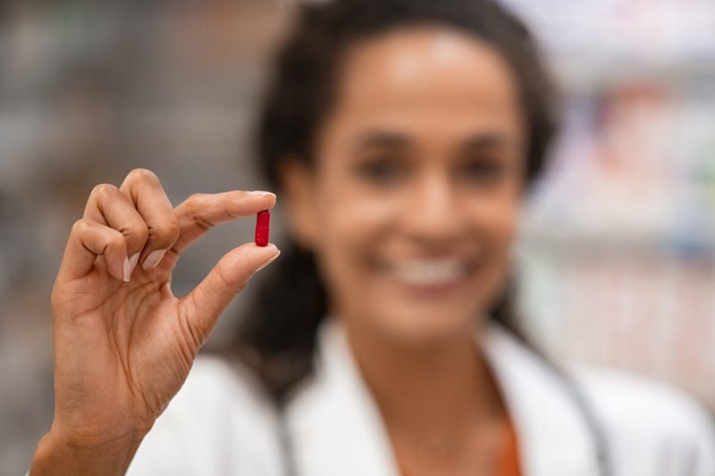 Woman holding pill stock photo.
