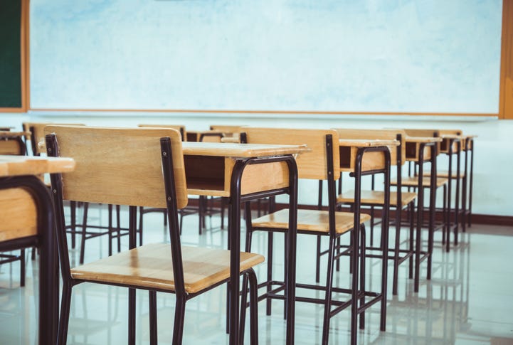 Empty classroom in a high school. Desks lined up in front of a white board.