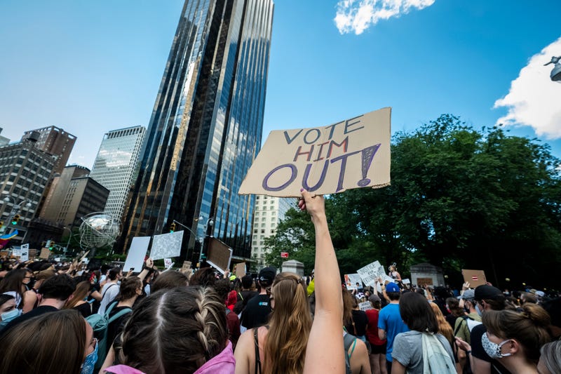 A protester holds a homemade sign above their head that says, "Vote Him Out!" in front of Trump International Hotel and Tower at Columbus Circle on June 14, 2020.
