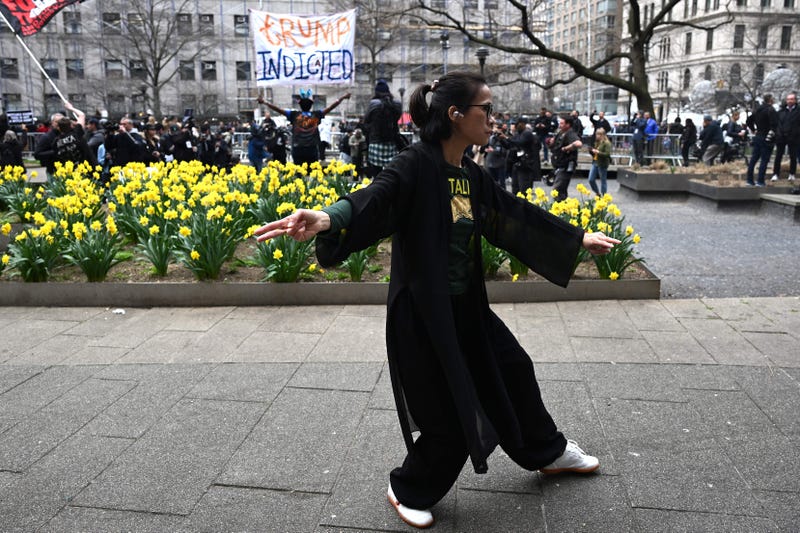 A woman practices tai chi as people protest outside the D.A.'s office on April 4, 2023.