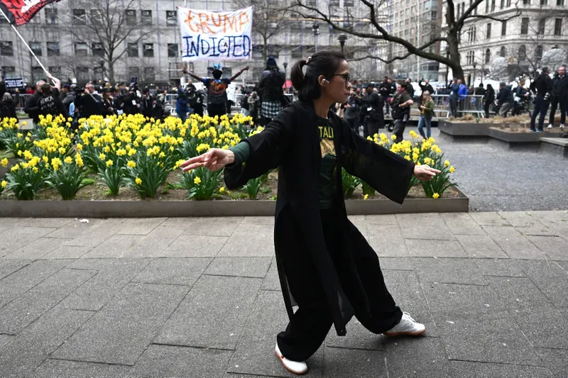A woman practices tai chi as people protest outside the D.A.'s office on April 4, 2023. 