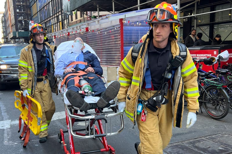Members of the Fire Department of New York (FDNY) Emergency Medical Services (EMS) move an injured person on a gurney at the scene of a parking garage that collapsed in lower Manhattan, New York City, on April 18, 2023.