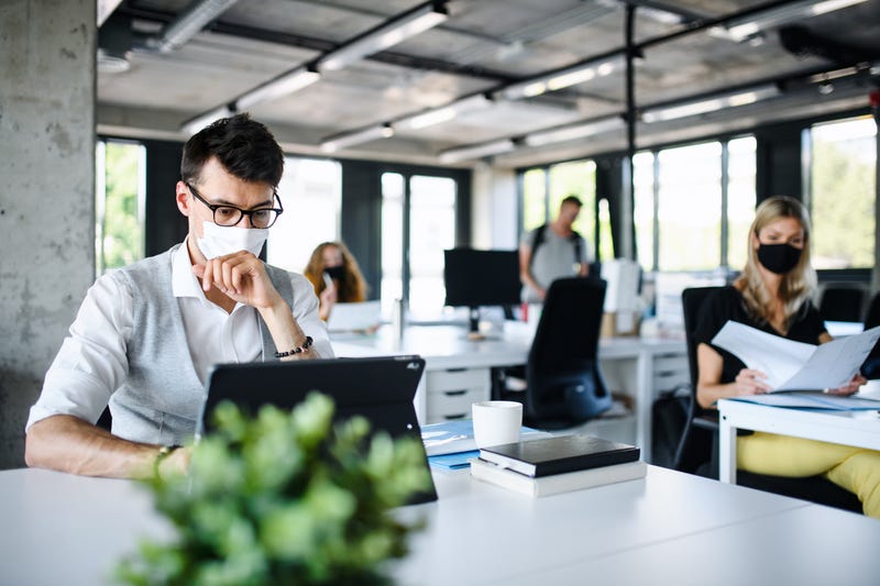 Young people with face masks back at work or school in office after lockdown