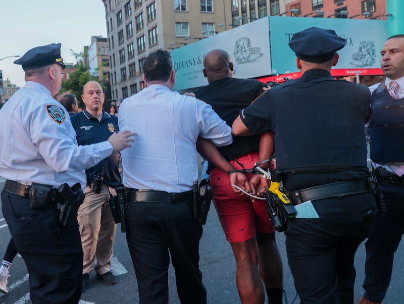 Police take a person into custody at the vigil on May 8, 2023
