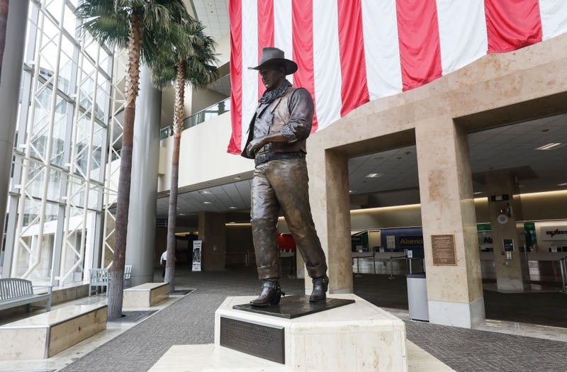 A statue of John Wayne is on display beneath an American flag in John Wayne Airport, located in Orange County, on June 28, 2020 in Santa Ana, California.