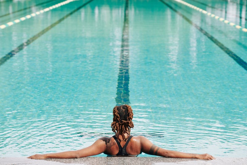 A Black woman in a pool without a swim cap. 