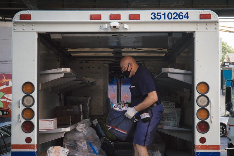 USPS postman loading mail in truck 