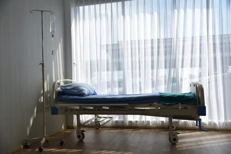 An empty patient bed in a hospital room.