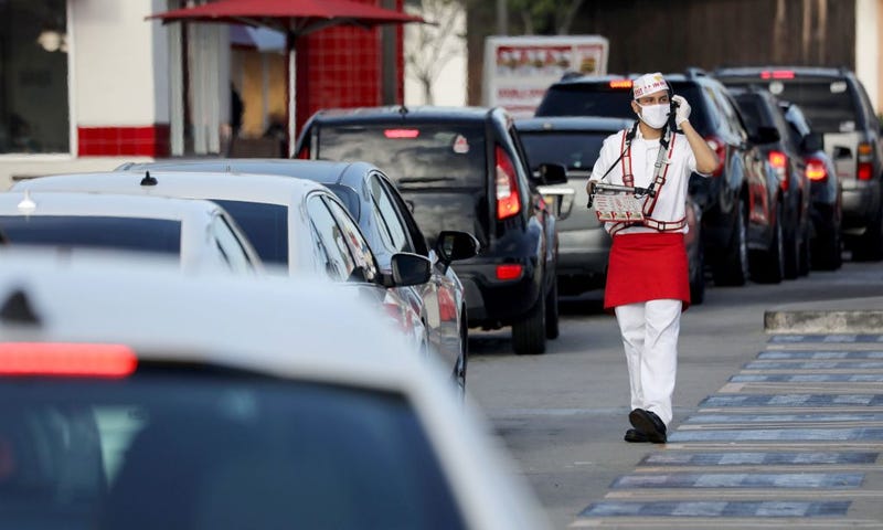 A worker wears a face covering while taking orders from motorists in the drive-through lane at an In-N-Out Burger restaurant amid the COVID-19 pandemic on July 1, 2020 in Los Angeles, California.