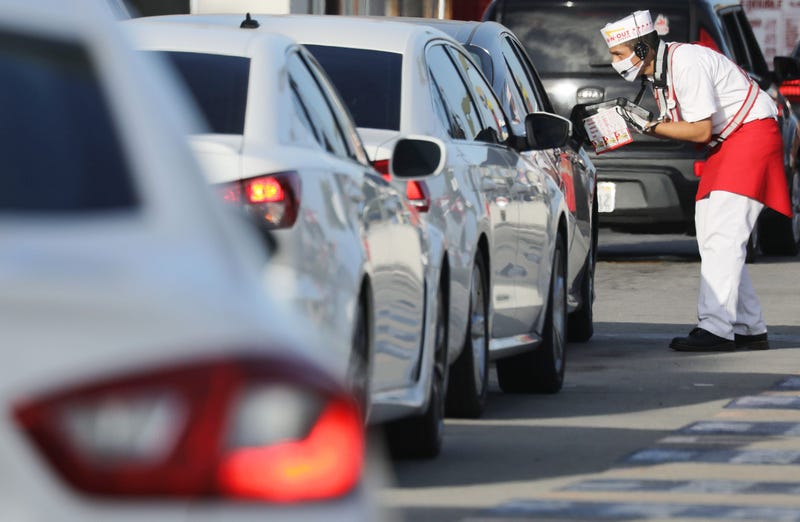 A worker wears a face covering while taking orders from motorists in the drive-through lane at an In-N-Out Burger restaurant amid the COVID-19 pandemic on July 1, 2020 in Los Angeles.