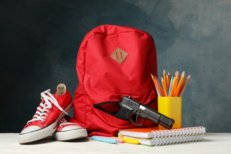 School accessories and gun on white wooden table. School violence
