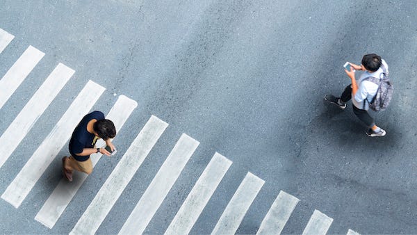 People looking at smartphones while walking through crosswalk