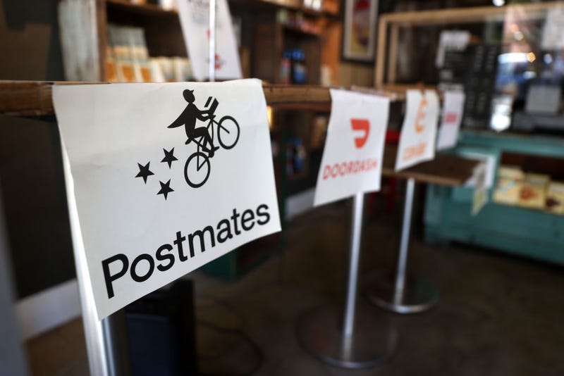 A Postmates sign is displayed next to other deliver companies at a restaurant on July 06, 2020 in San Francisco, California.