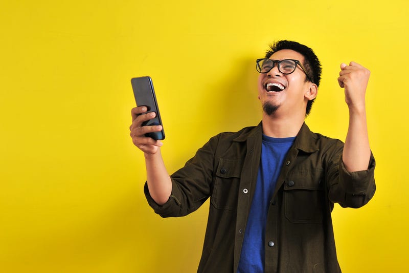 Man holding smartphone with winning gesture
