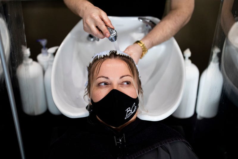 A customer wears a face mask while having her hair washed at a salon.