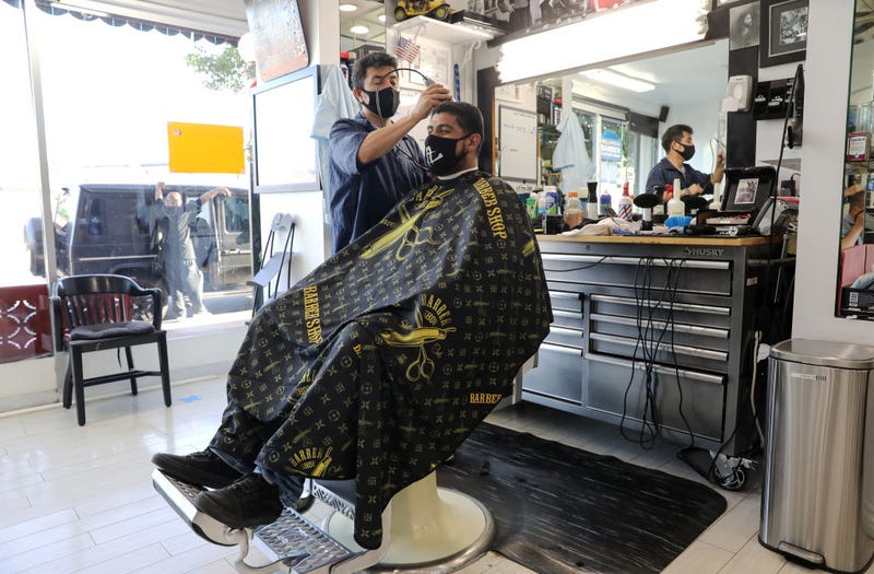 FILE - A barber and his client wear face masks in the Hollywood Barber Shop shortly before closing amid new restrictions due to the COVID-19 pandemic on July 13, 2020 in Los Angeles.