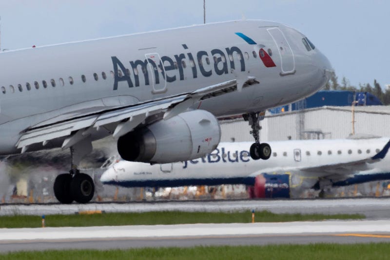 An American Airlines plane lands on a runway near a parked JetBlue plane at the Fort Lauderdale-Hollywood International Airport on July 16, 2020 in Fort Lauderdale, Florida.