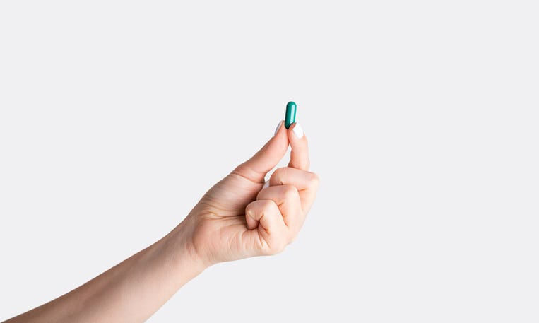 Hand holding a pill.