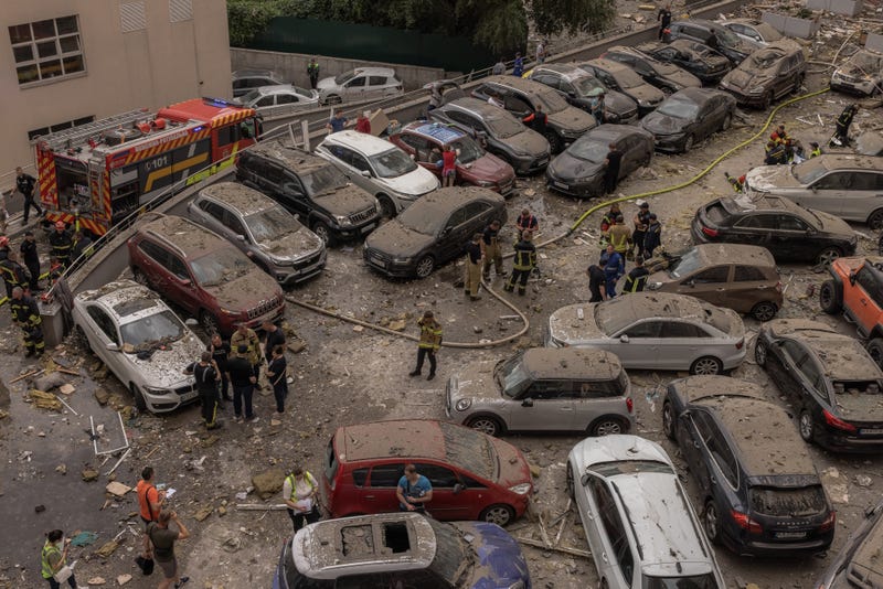 Police, emergency personnel and residents gather at a car park with damaged cars next to the heavily damaged apartment building that was hit by a downed Russian missile on June 24, 2023 in Kyiv, Ukraine.