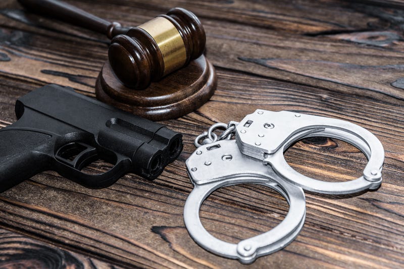 handcuffs, a judge hammer, a gun on a wooden background. 