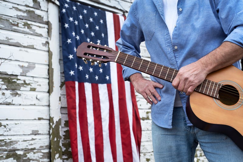 FILE: Man with a guitar in front of an American flag.
