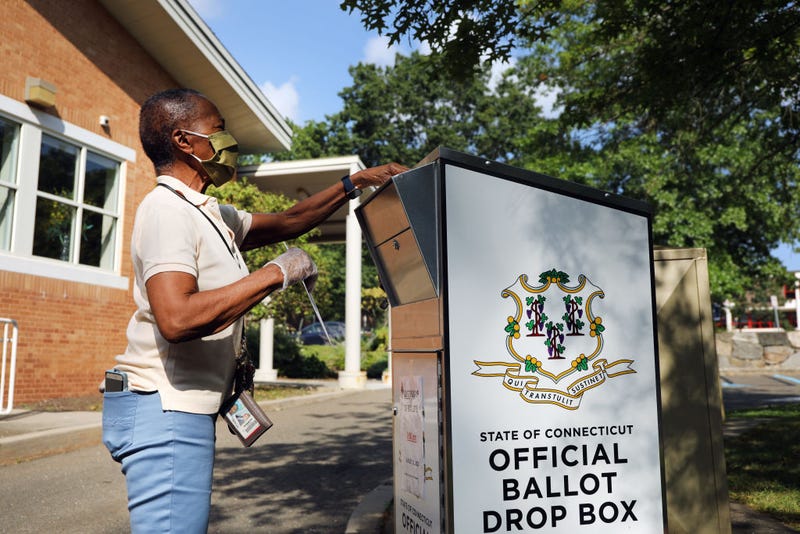 A woman drops her Connecticut 2020 presidential primary ballot at a secure ballot drop box at a Stamford library on August 11, 2020 in Stamford, Connecticut