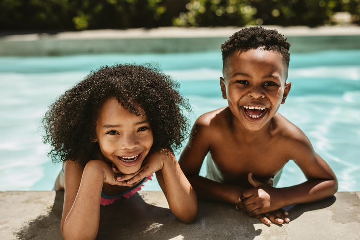 Cute brother and sister leaning on pool edge