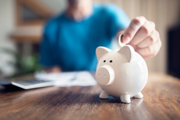 Man putting a coin into a pink piggy bank