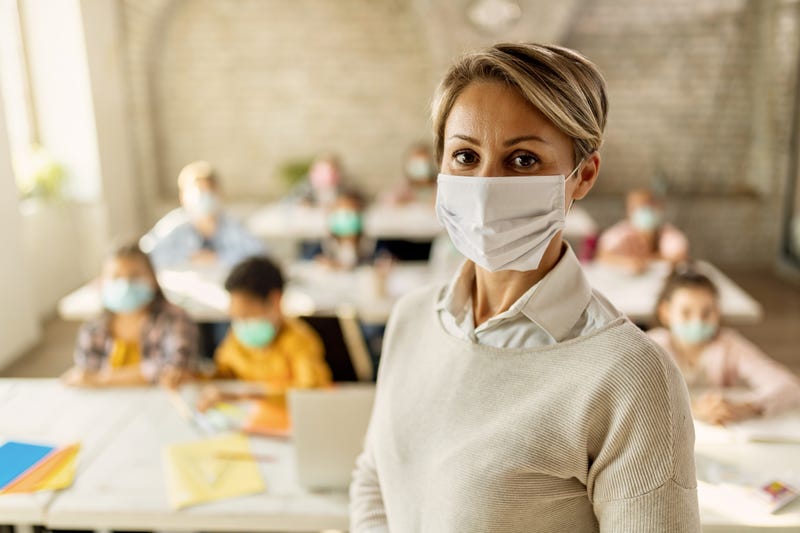 Elementary school teacher with protective face mask in the classroom