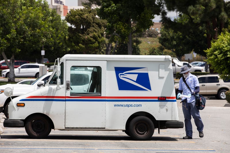 A postal worker standing next to a USPS truck