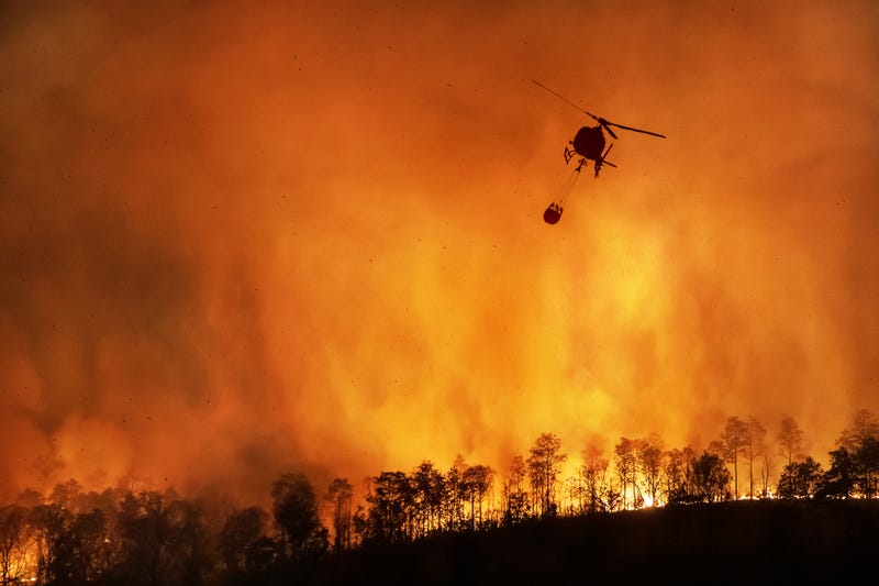 Fire fighting helicopter dropping water over wildfire. 