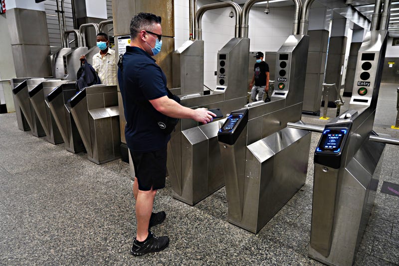 A commuter uses the OMNY tap-to-pay system.