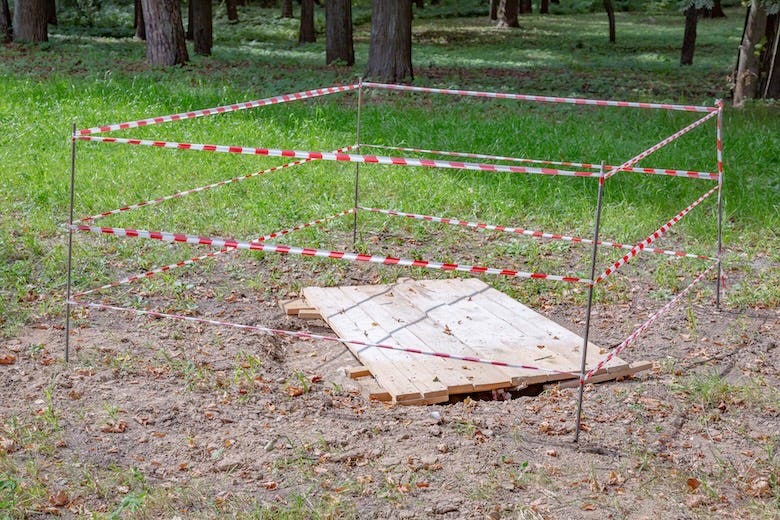 Red and white police tape in the city park. Sinkhole warning