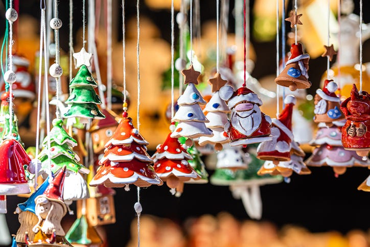 Hand-crafted, hand-painted Christmas ornaments hang from a display at a craft fair.