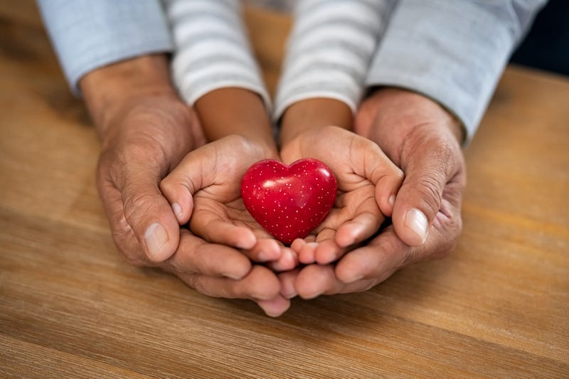 Stock image of child and parent's hands holding heart