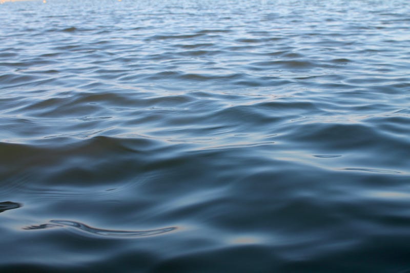 Calm shiny waves at sunset light on a lake surface