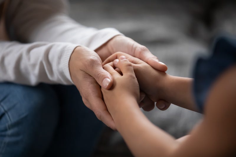 An adult holds a child's hands.