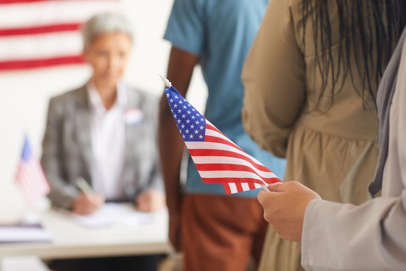 Person holding a flag while they wait in line to vote.